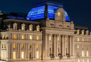 An outside shot of the Centro Cultural Kirchner building at night. The glass roof is glowing with blue light.