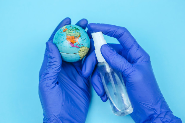 Hands in latex gloves sanitizing a small globe